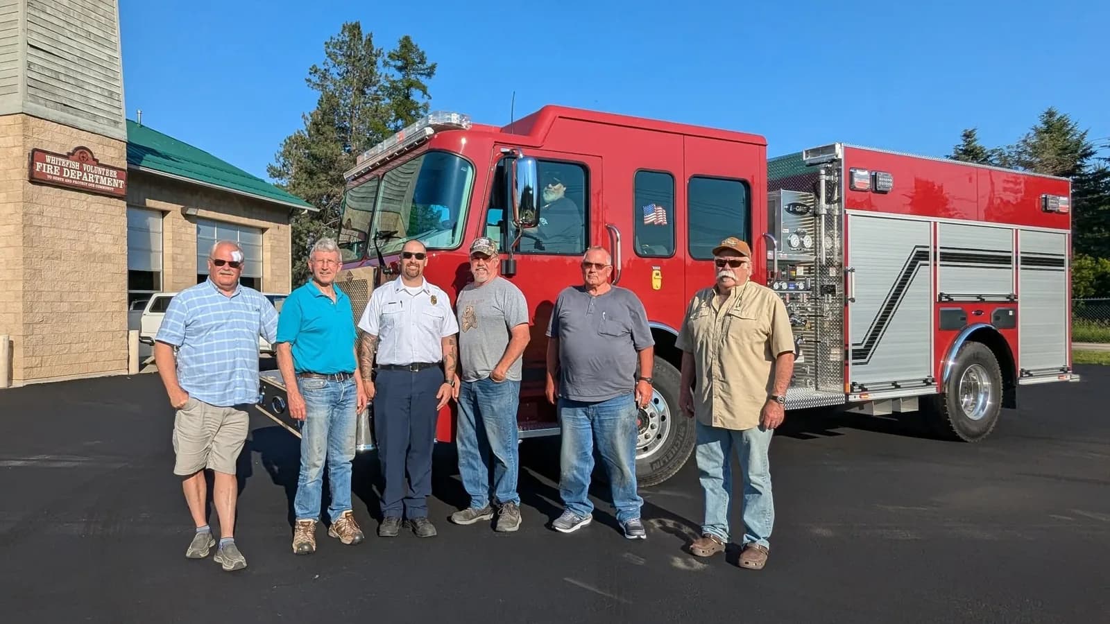 Six people standing in front of a fire engine at the Whitefish Volunteer Fire Department